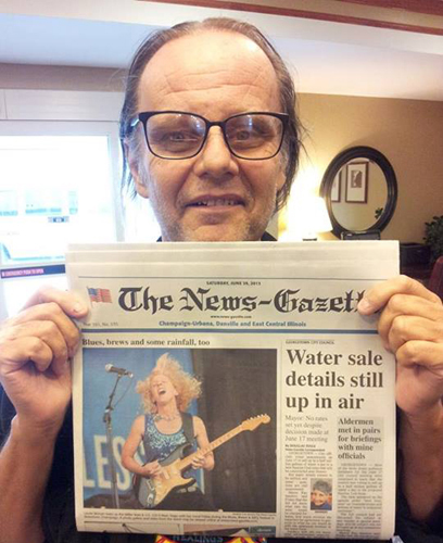 Walter Trout holds up front page of the News Gazette after the Laurie Morvan Band's red hot performance at the Champaign Blues, Brews and BBQ Festival